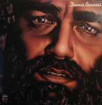 Portrait of Demis Roussos, a singer, with a distinctive hairstyle, captured for Rectangle Triangle brand in a vibrant, artistic setting.