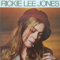 Rectangle Triangle Rickie Lee Jones logo on a navy background, featuring a minimalist geometric design with sleek lines and modern style.